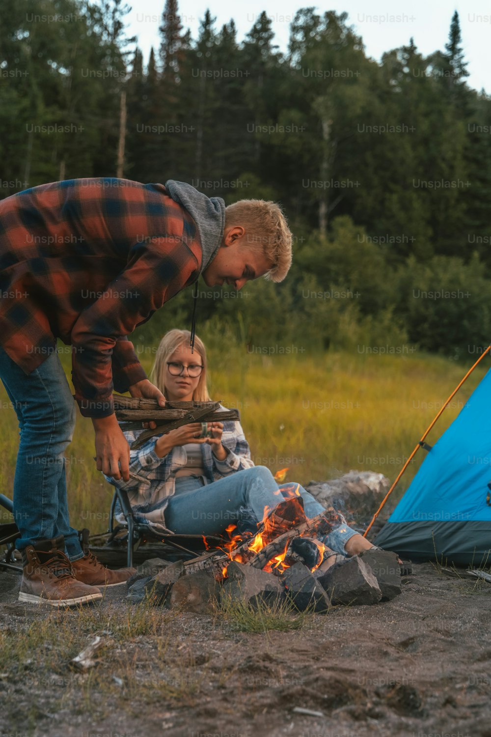 a man and a woman setting up a campfire