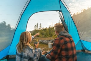 a man and a woman sitting inside of a tent