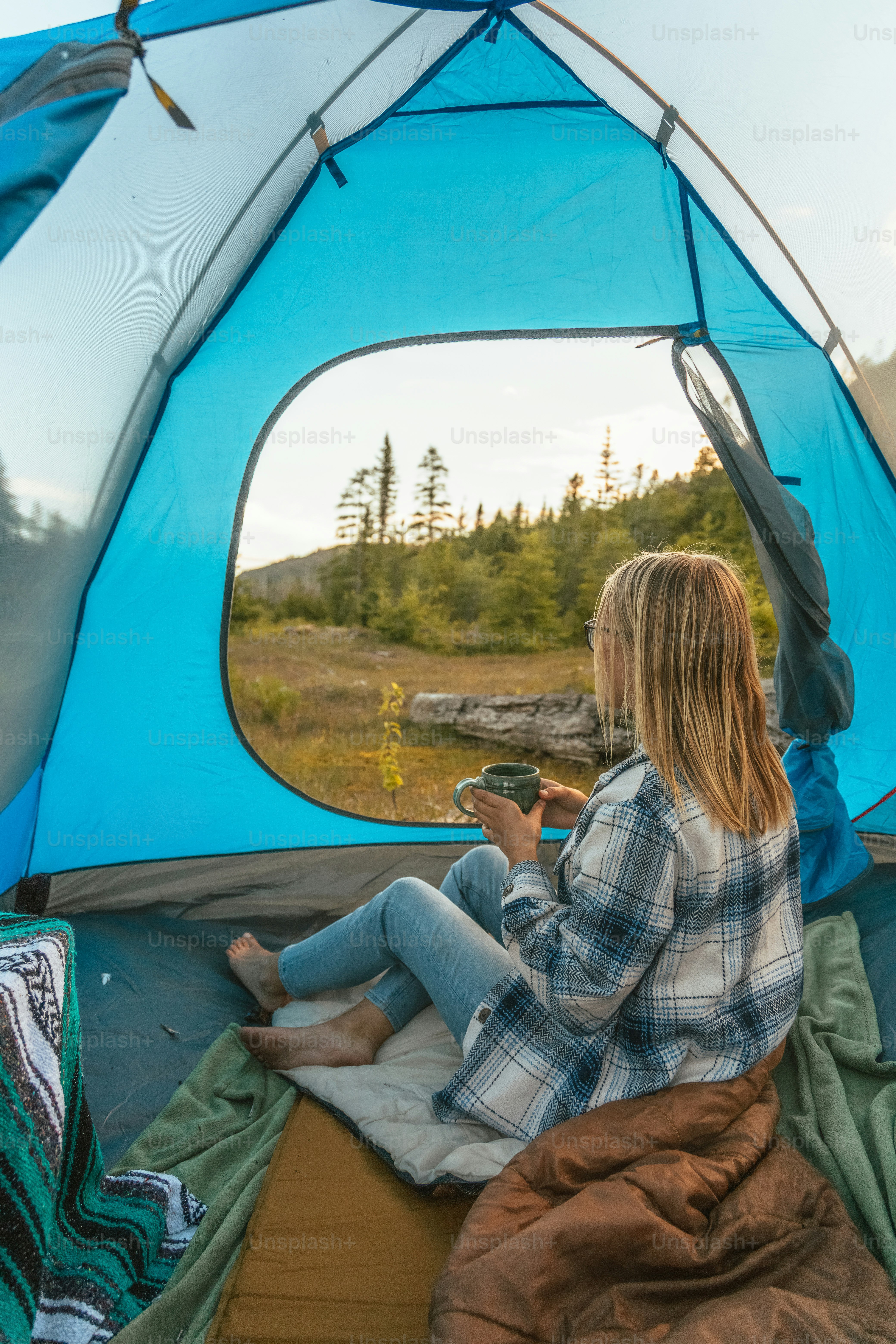 a woman sitting inside of a blue tent