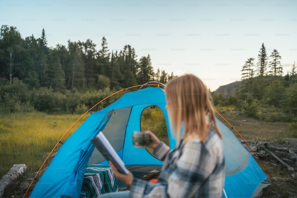 a woman sitting in front of a blue tent