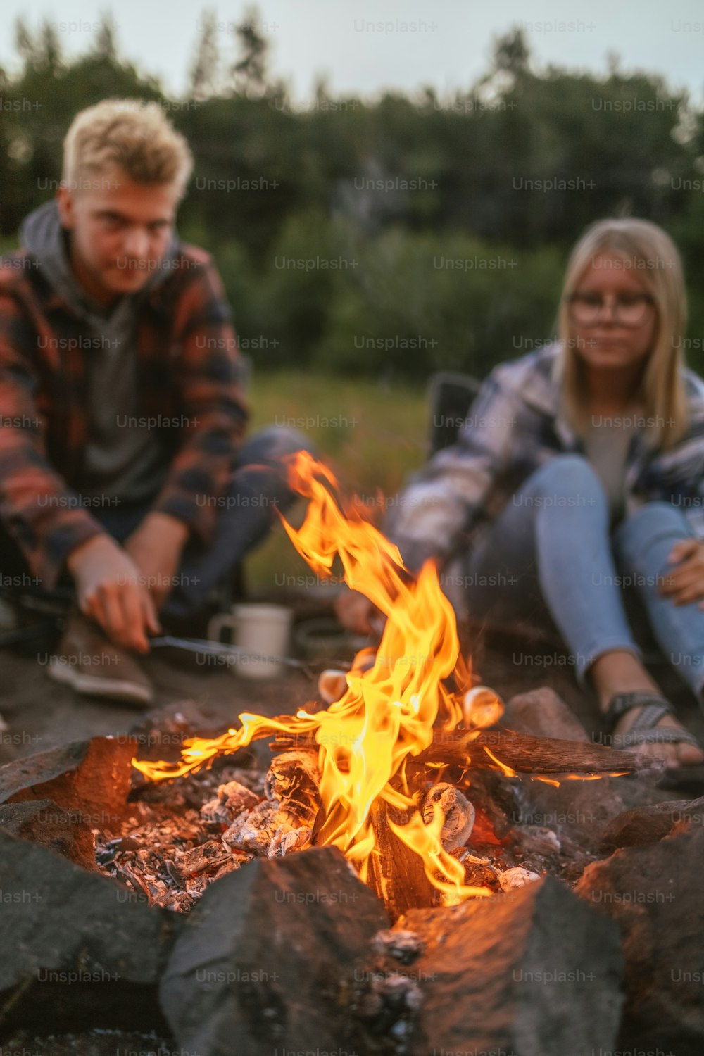 um homem e uma mulher sentados ao lado de uma fogueira