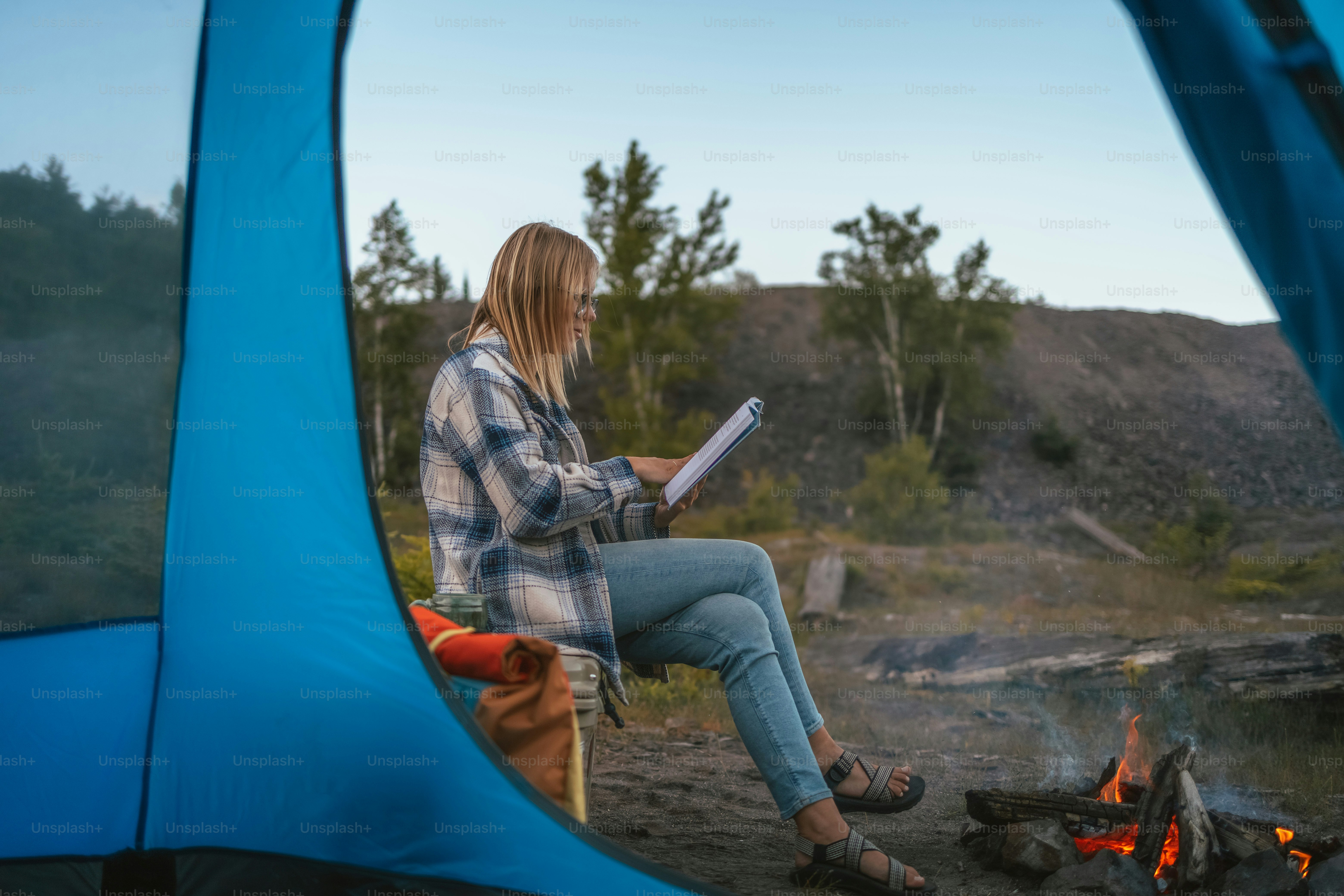 a woman sitting in a chair next to a campfire