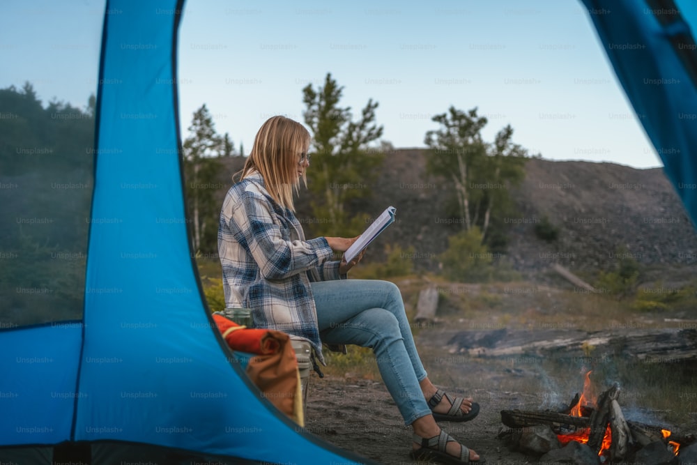 a woman sitting in a chair next to a campfire