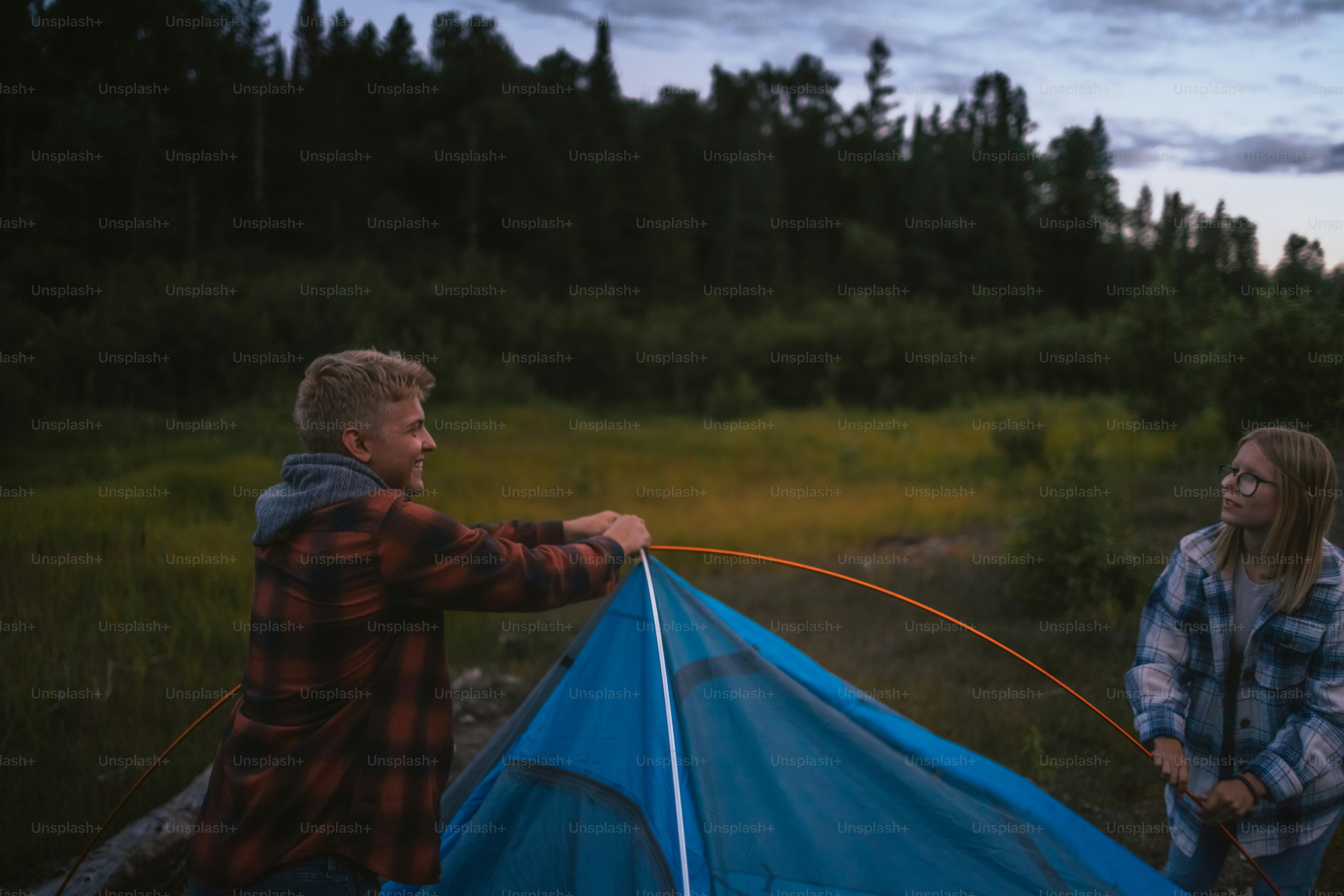 a man and a woman standing next to a blue tent