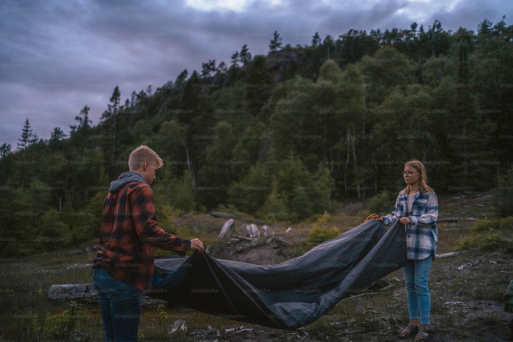a man and a woman holding a tarp in the woods
