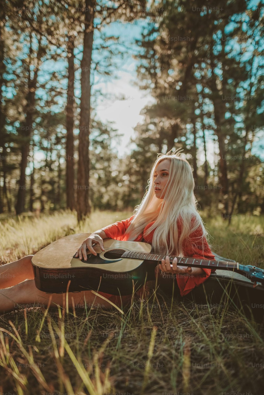 a woman sitting in the grass with a guitar