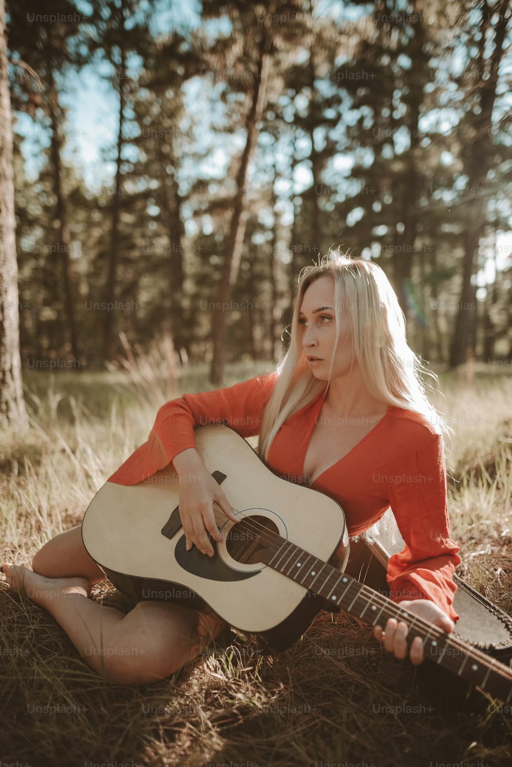 a woman sitting in the grass with a guitar