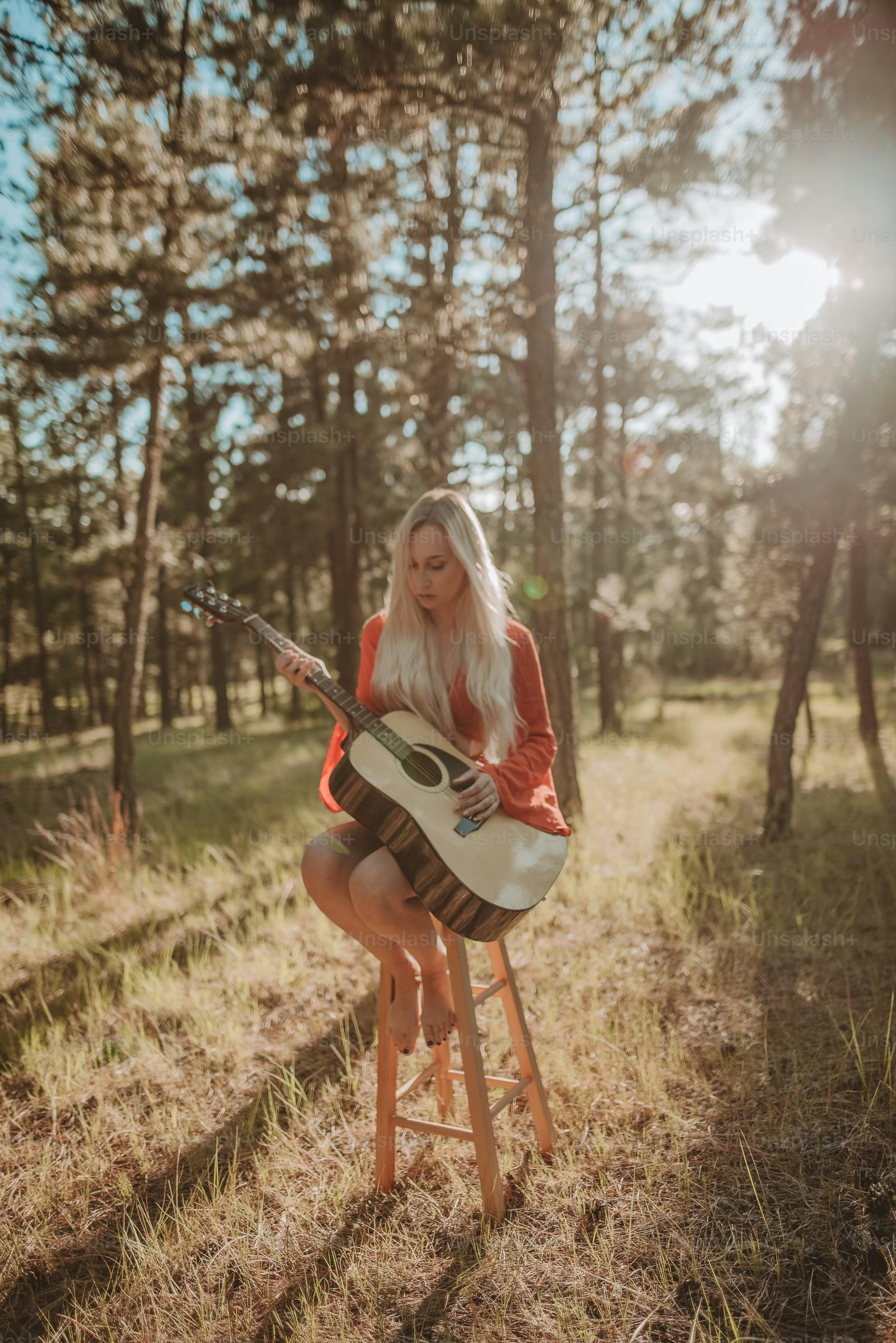 a woman sitting on a stool playing a guitar