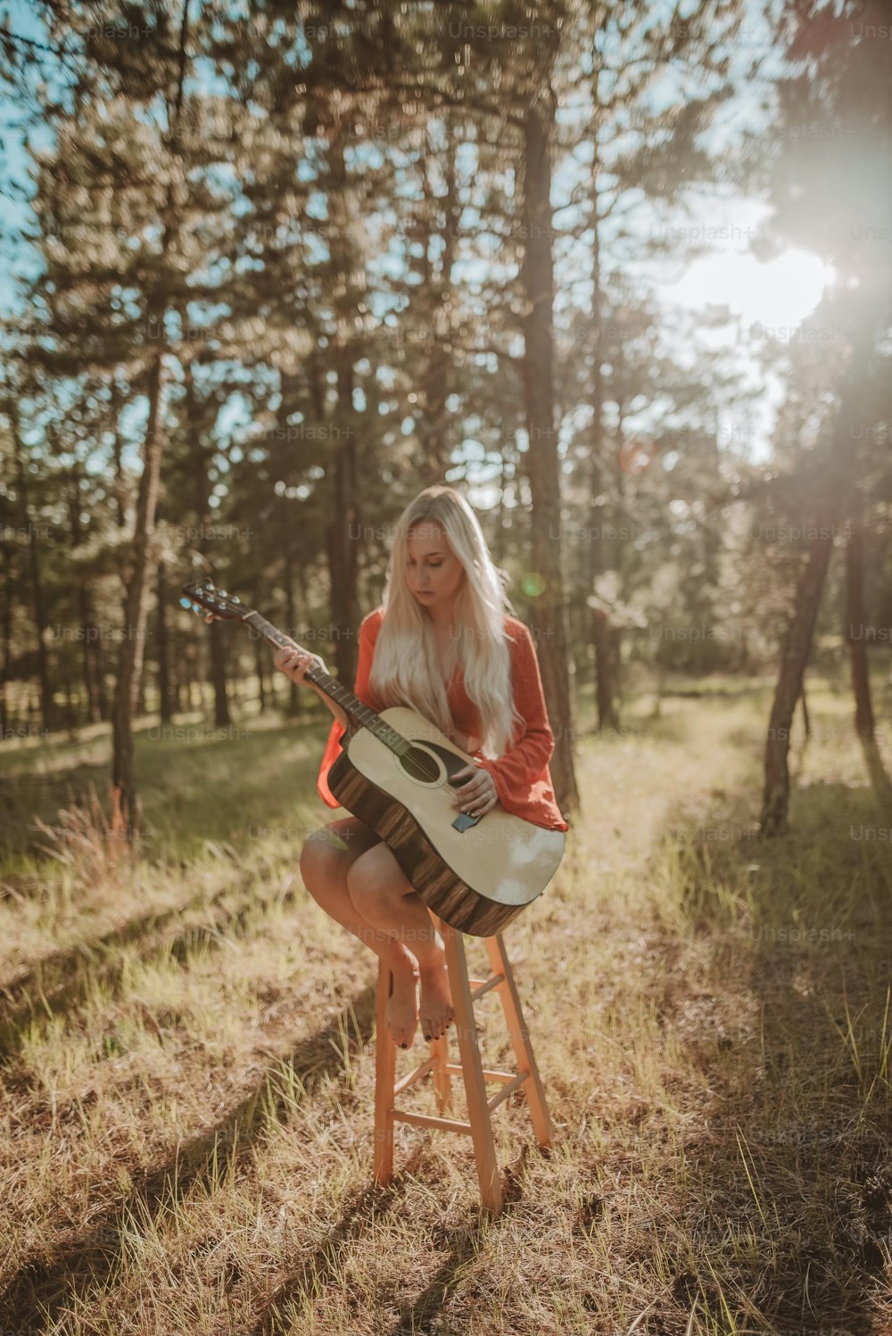 a woman sitting on a stool playing a guitar