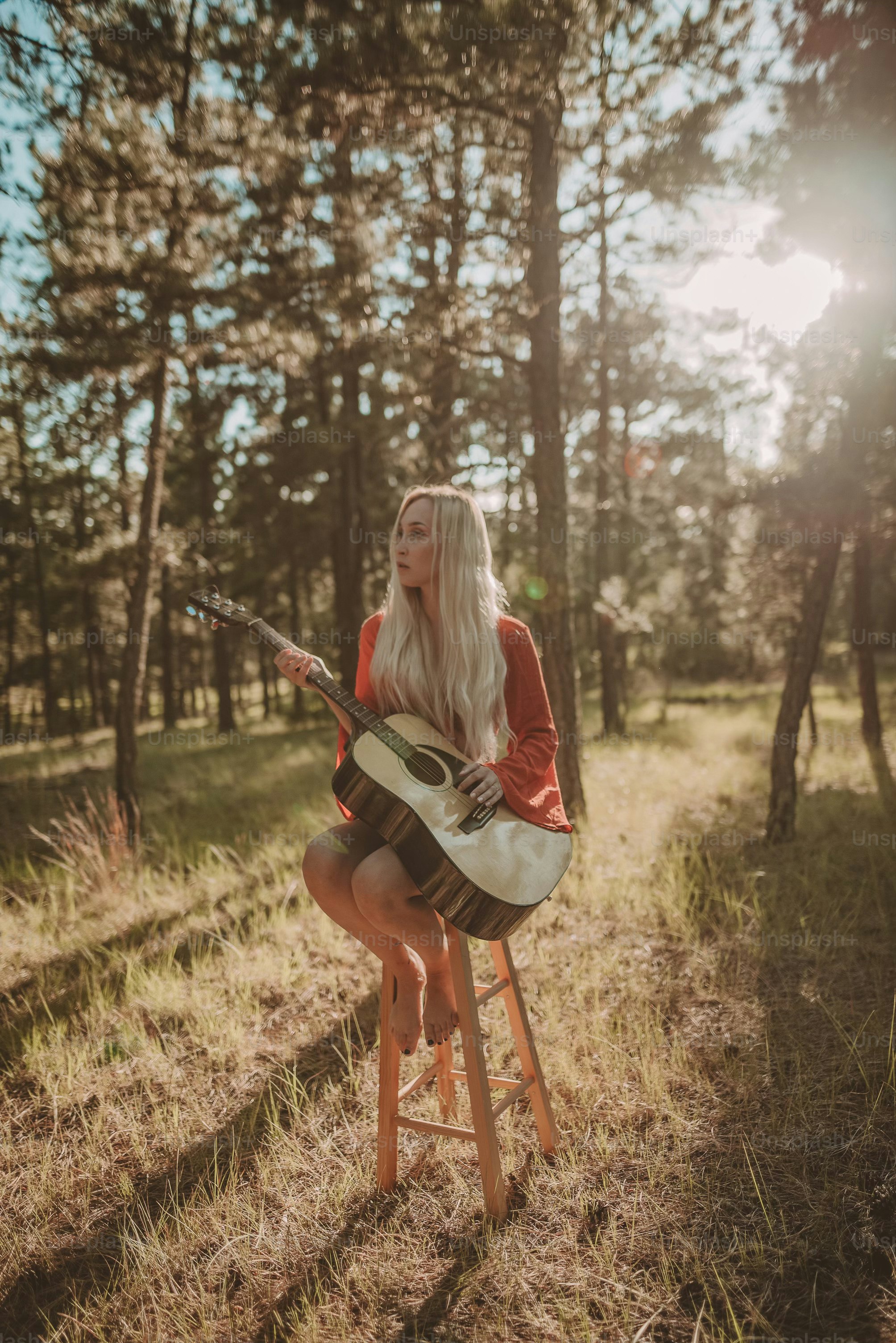 a woman sitting on a stool playing a guitar