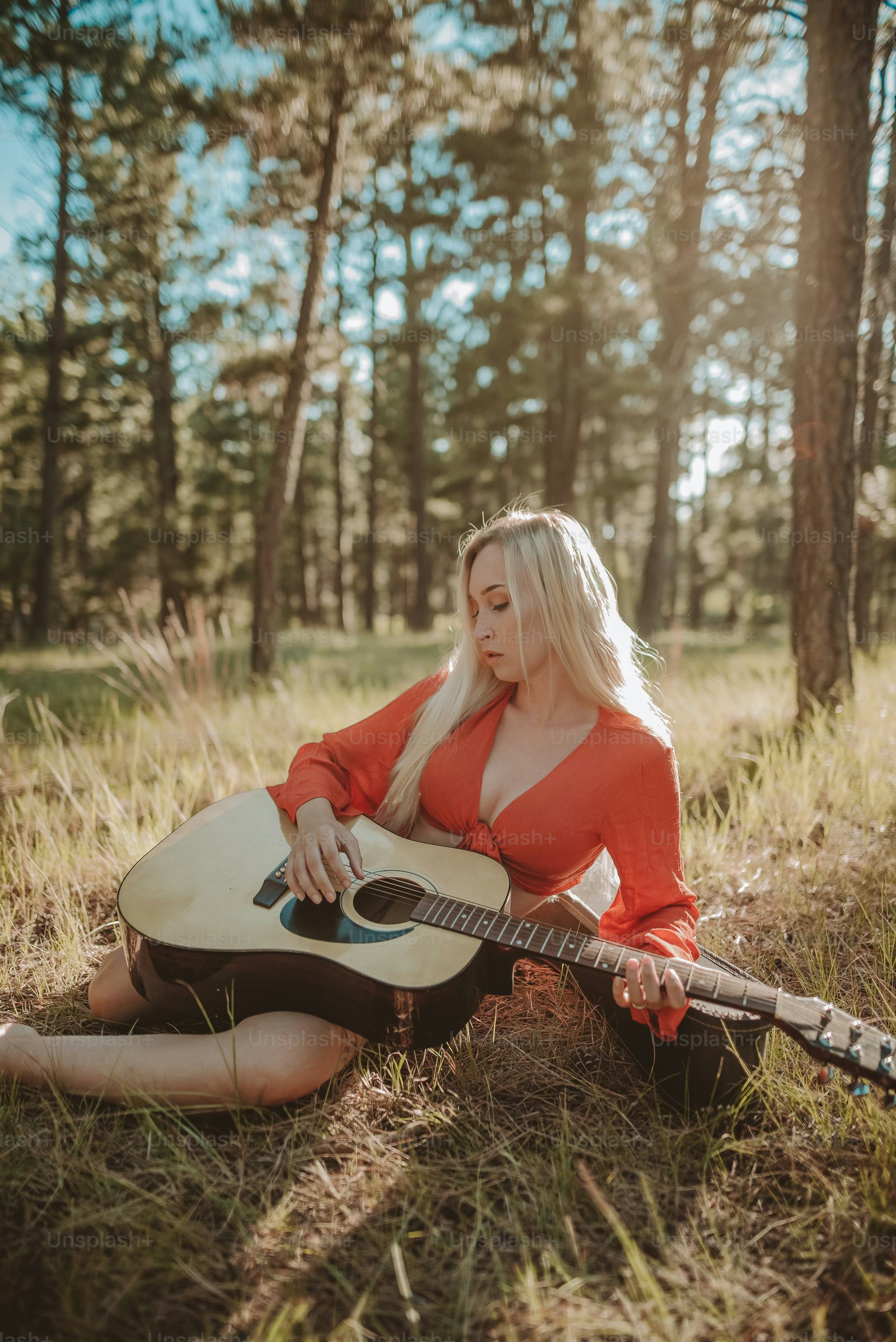 a woman sitting in the grass with a guitar