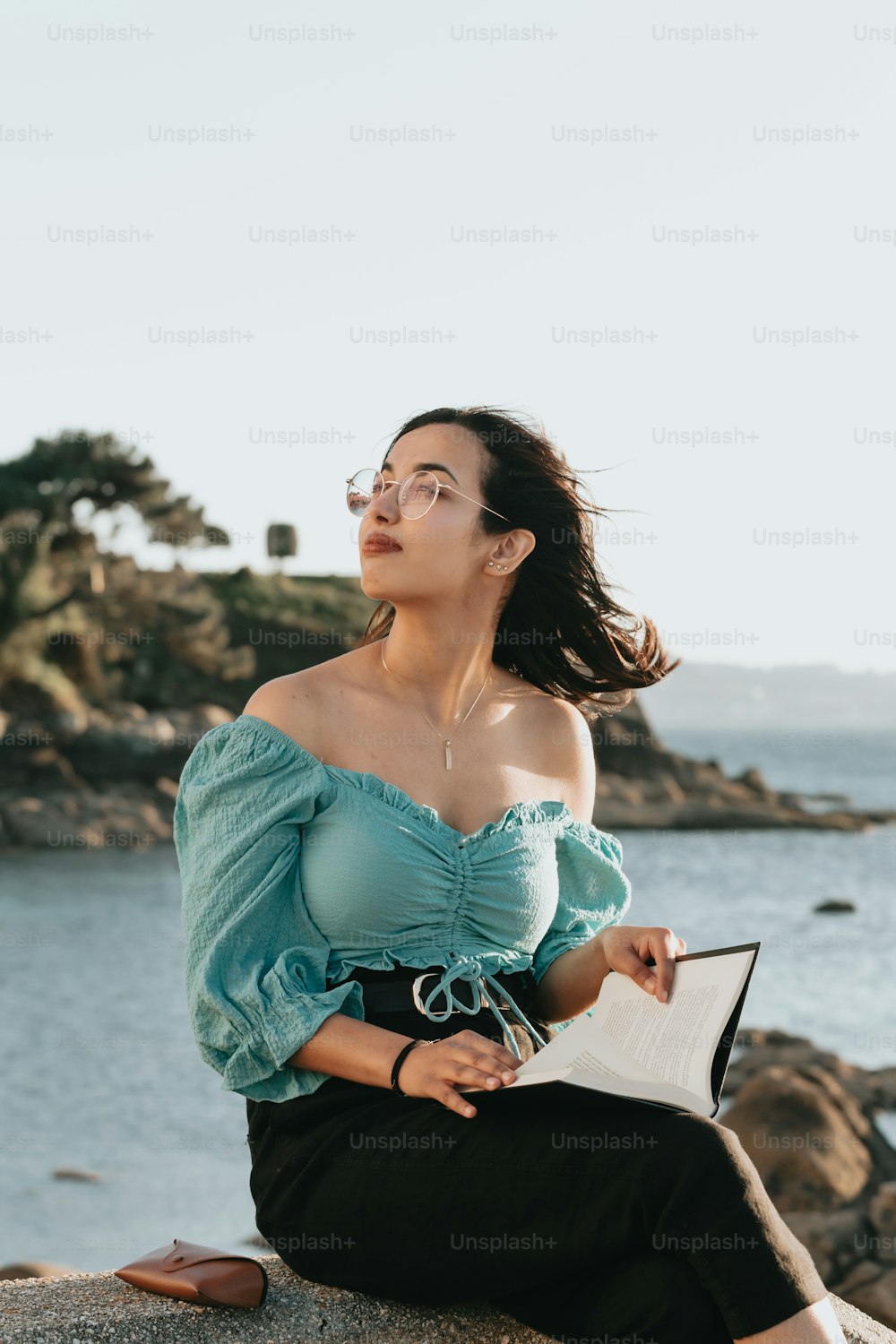 a woman sitting on a rock looking up at the sky