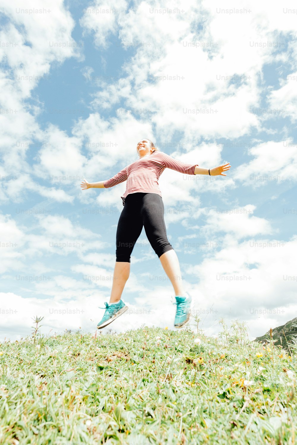 a woman in a pink shirt and black shorts jumping in the air