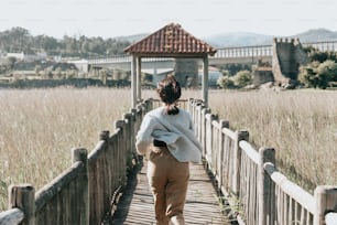野原の木の橋を渡って歩く女性