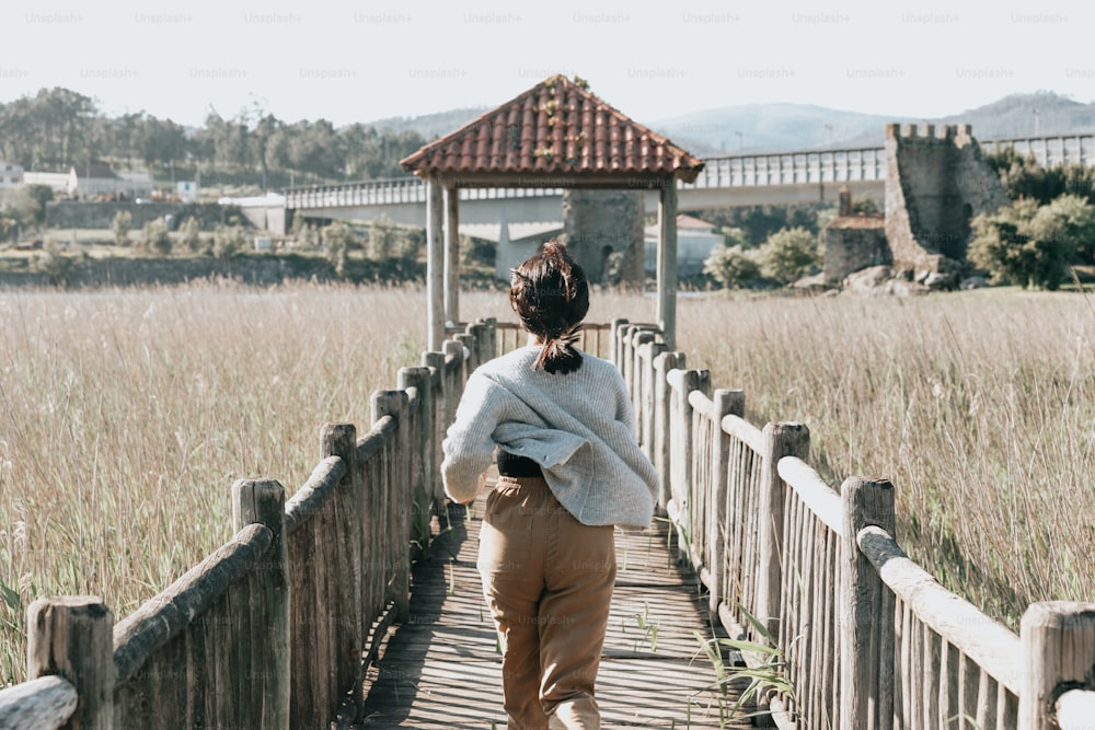 Una mujer caminando por un puente de madera en un campo