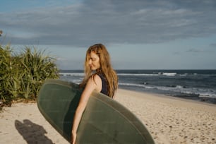 uma mulher segurando uma prancha de surf em uma praia