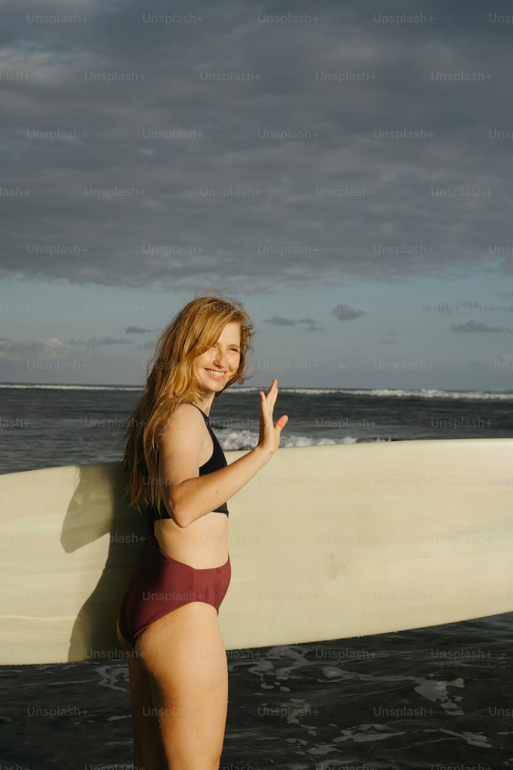a woman in a bikini holding a surfboard on the beach
