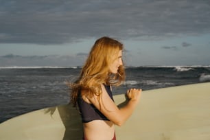 Una mujer en bikini sosteniendo una tabla de surf en la playa
