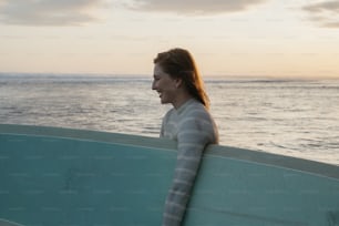 Eine Frau hält ein Surfbrett am Strand in der Hand