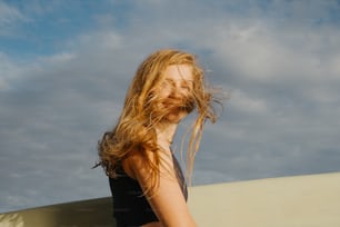 a woman with long hair holding a surfboard