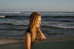 uma mulher em pé em uma praia segurando uma prancha de surf