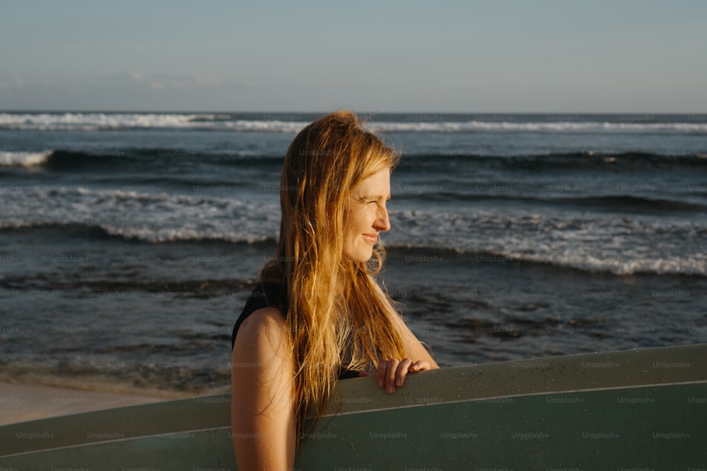 Eine Frau, die an einem Strand steht und ein Surfbrett hält