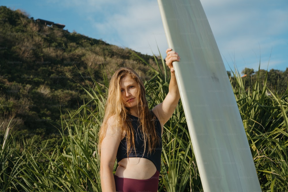 a woman holding a surfboard in front of a mountain