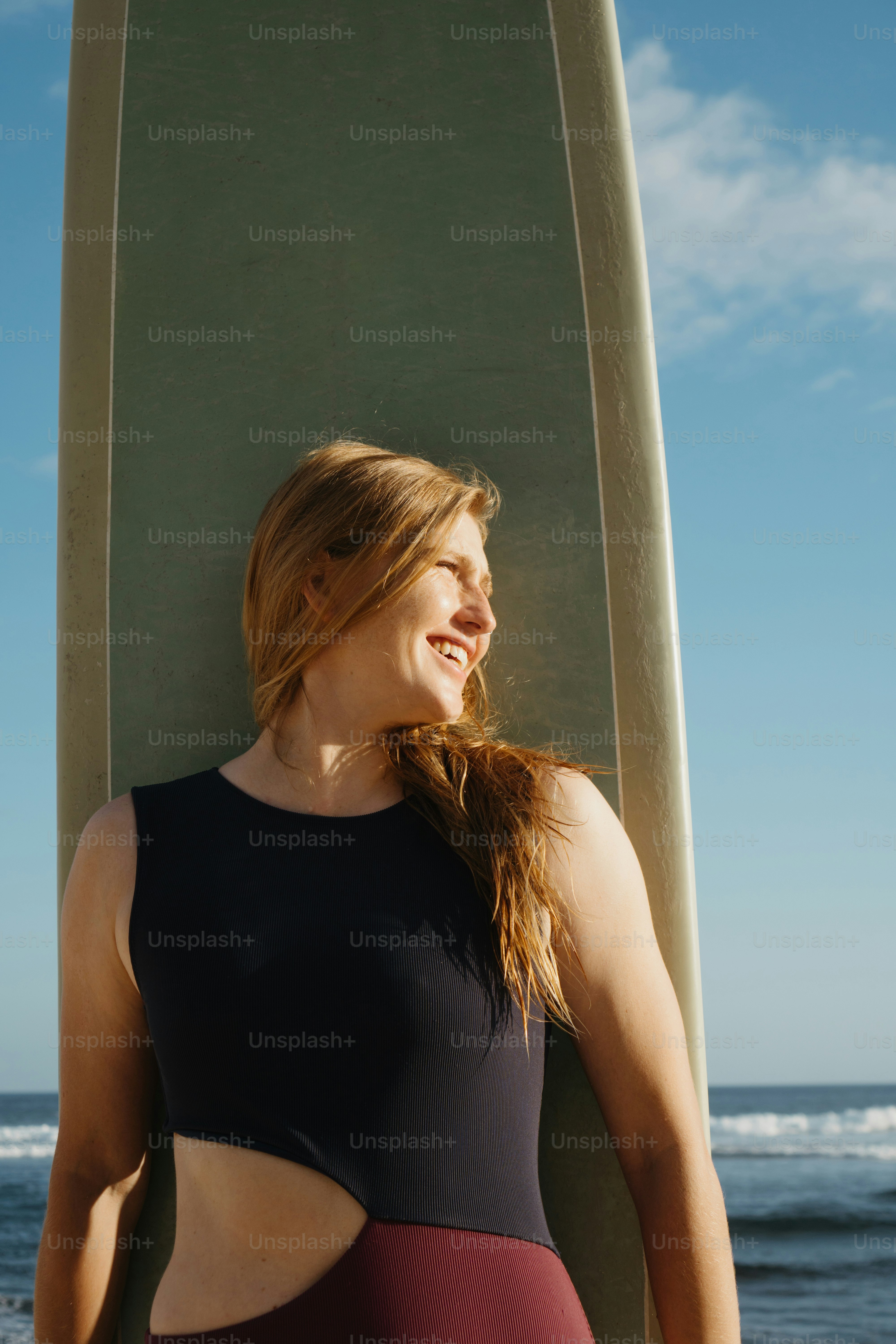 a woman standing next to a surfboard on the beach