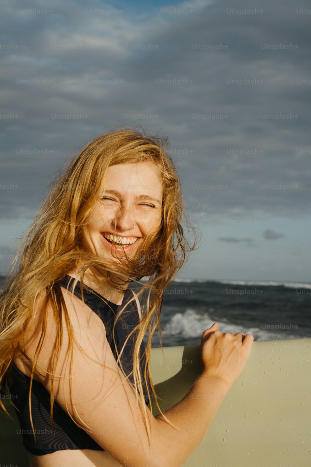 uma mulher com longos cabelos loiros segurando uma prancha de surfe