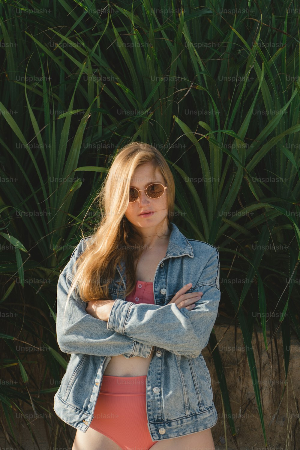 a woman in a bikini and jean jacket posing for a picture
