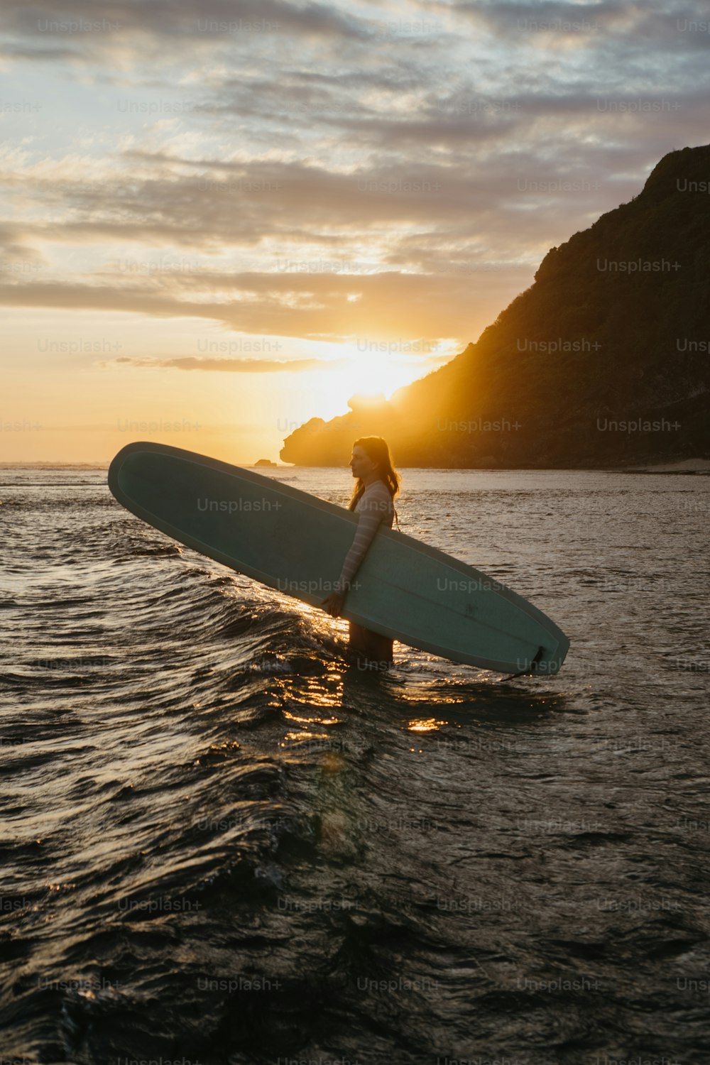 une personne tenant une planche de surf dans l’eau
