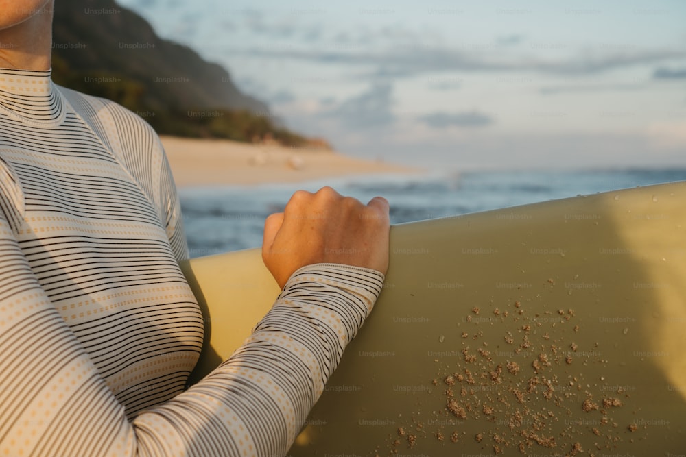한 여자가 해변에서 서핑보드를 들고 있다