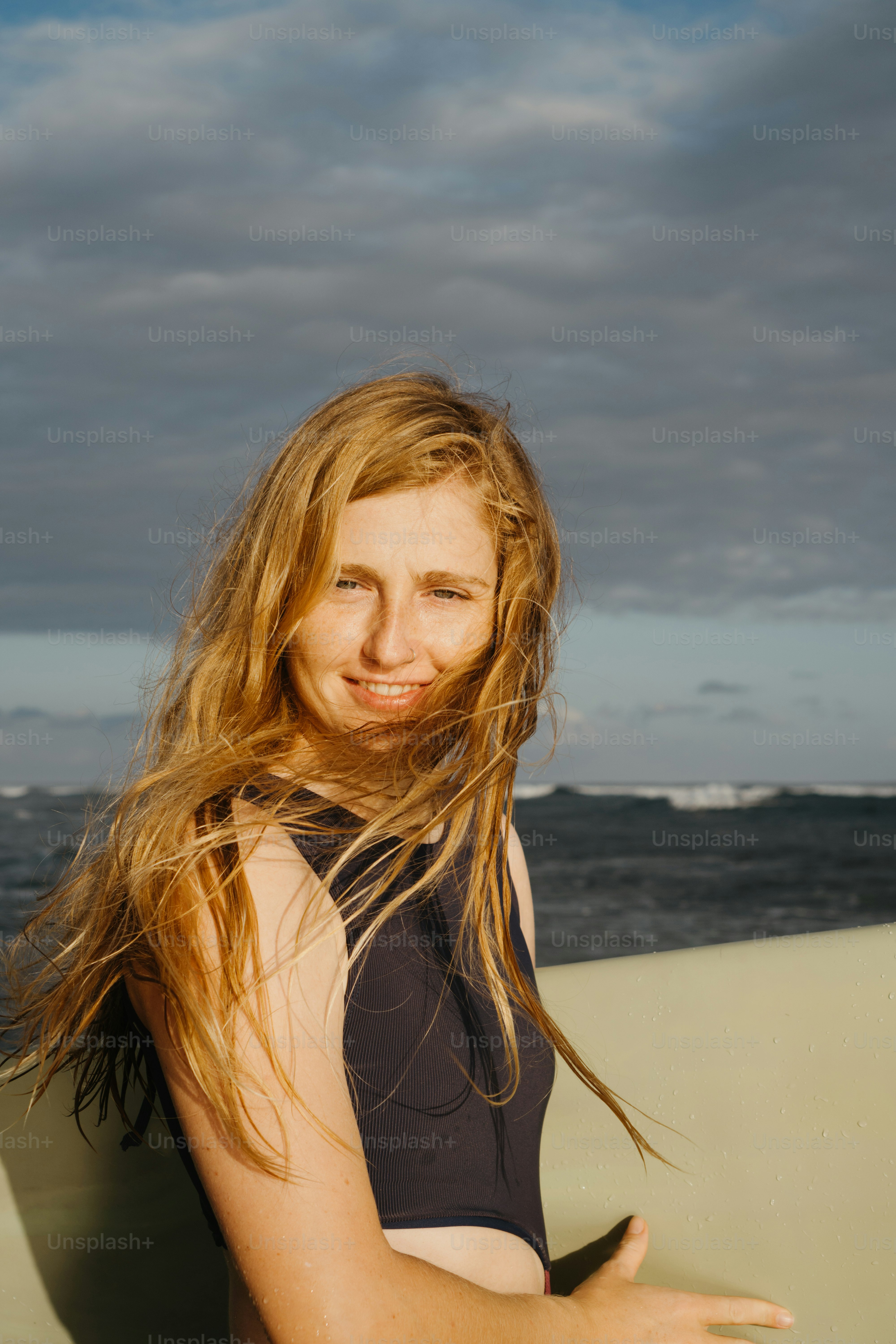 a woman with long hair is holding a surfboard