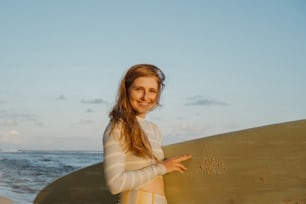 uma mulher em pé na praia segurando uma prancha de surf