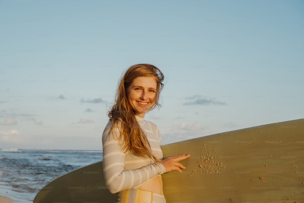 a woman standing on the beach holding a surfboard