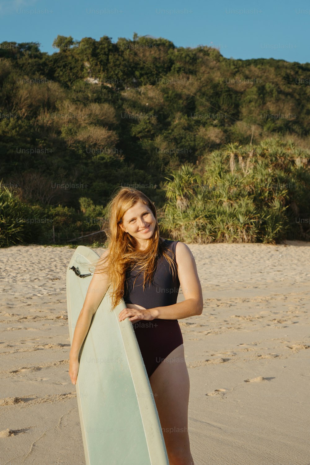 a woman holding a surfboard on a beach