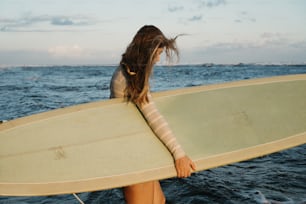 Una mujer sosteniendo una tabla de surf en el océano