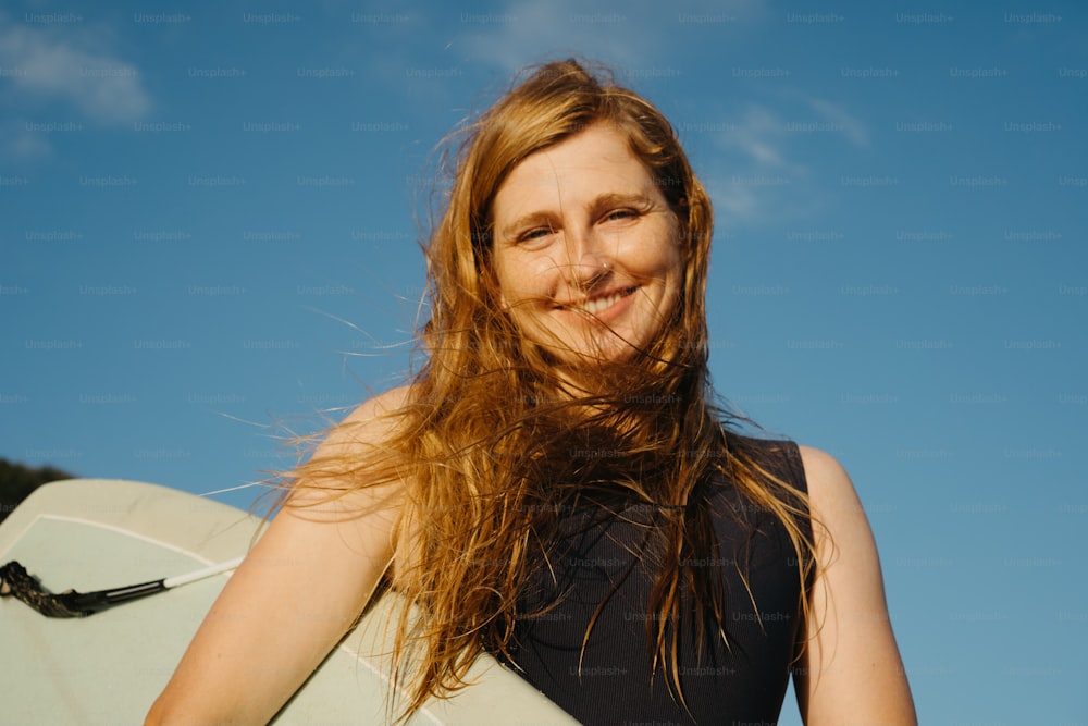 a woman holding a white surfboard under a blue sky