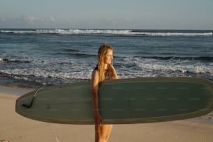 a woman standing on a beach holding a surfboard