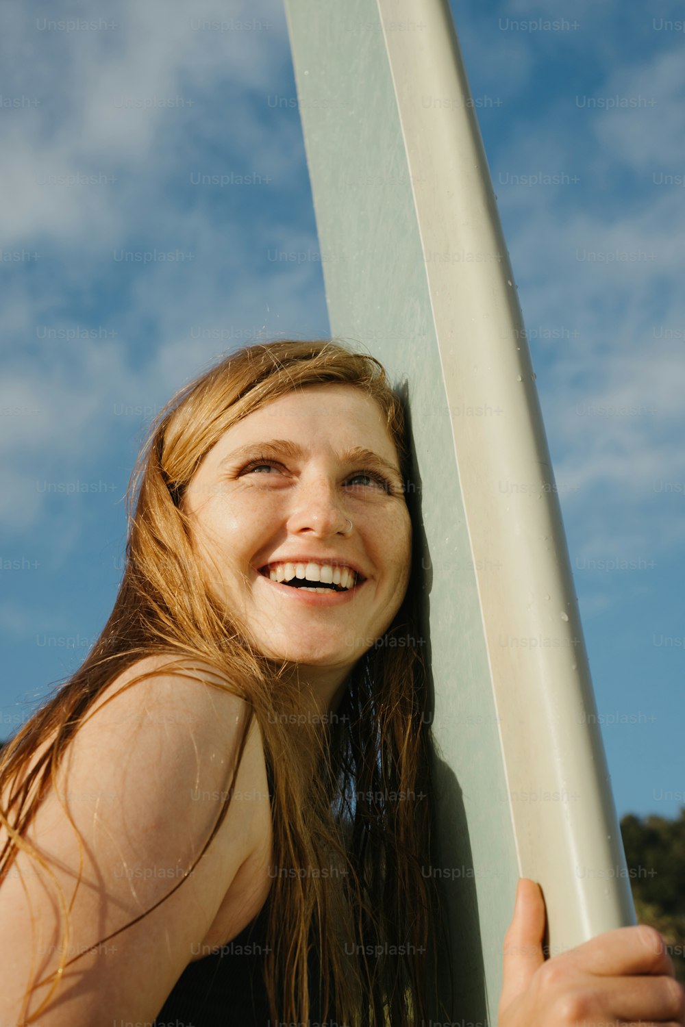 uma mulher está segurando uma prancha de surf e sorrindo