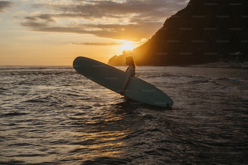 uma pessoa segurando uma prancha de surf na água