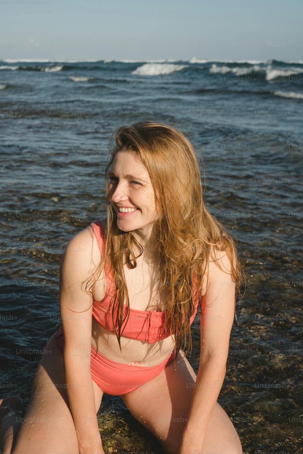 Eine Frau im Bikini sitzt am Strand
