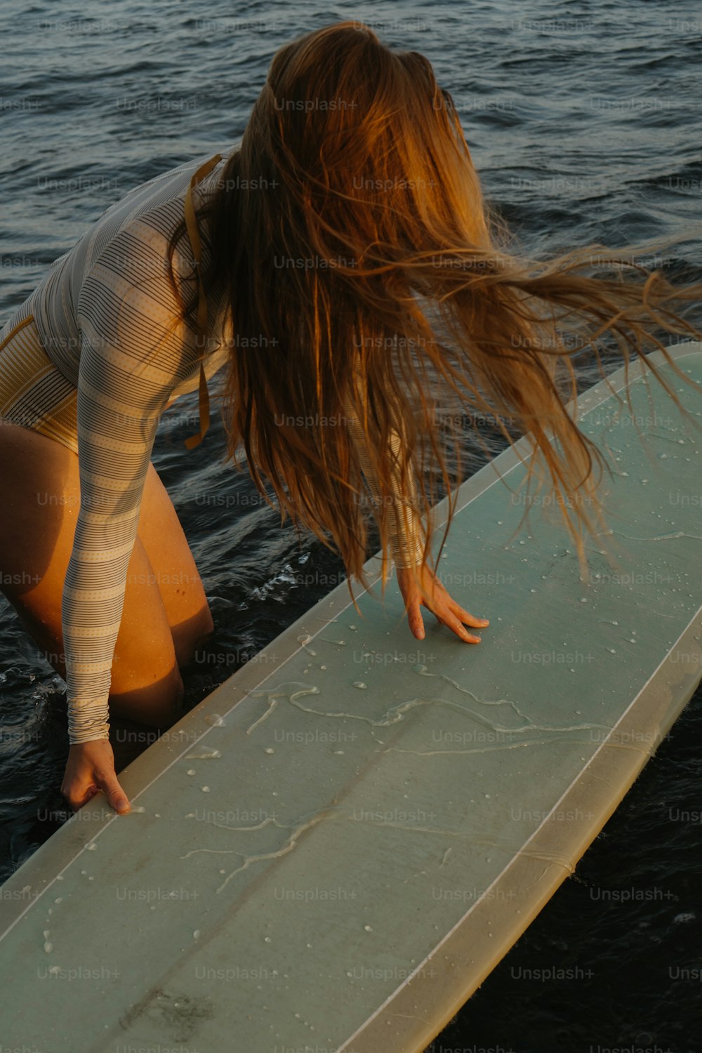 Una mujer arrodillada en una tabla de surf en el agua