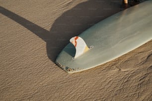 a surfboard laying on top of a sandy beach