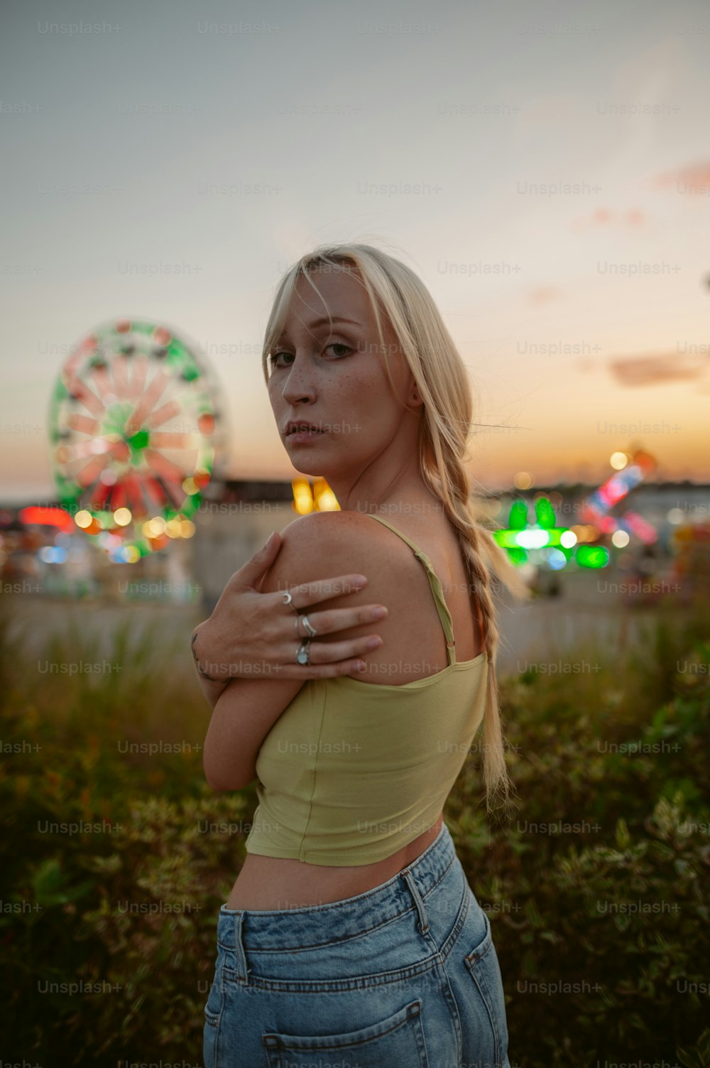 a woman in a yellow top standing in front of a ferris wheel