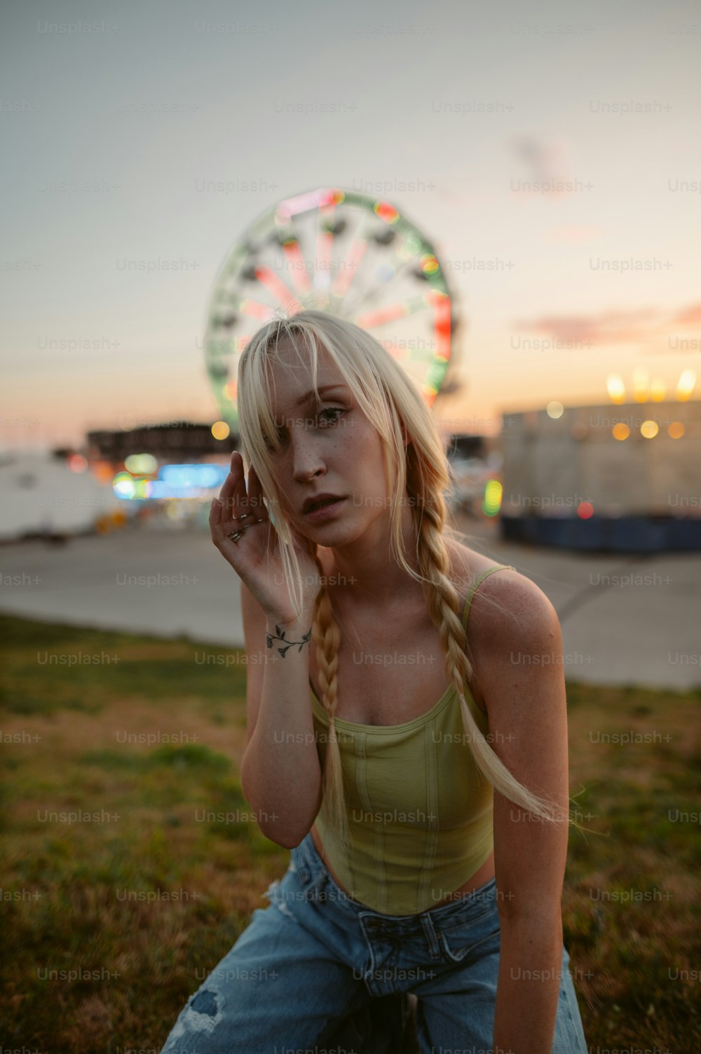 a woman sitting on the ground with a ferris wheel in the background