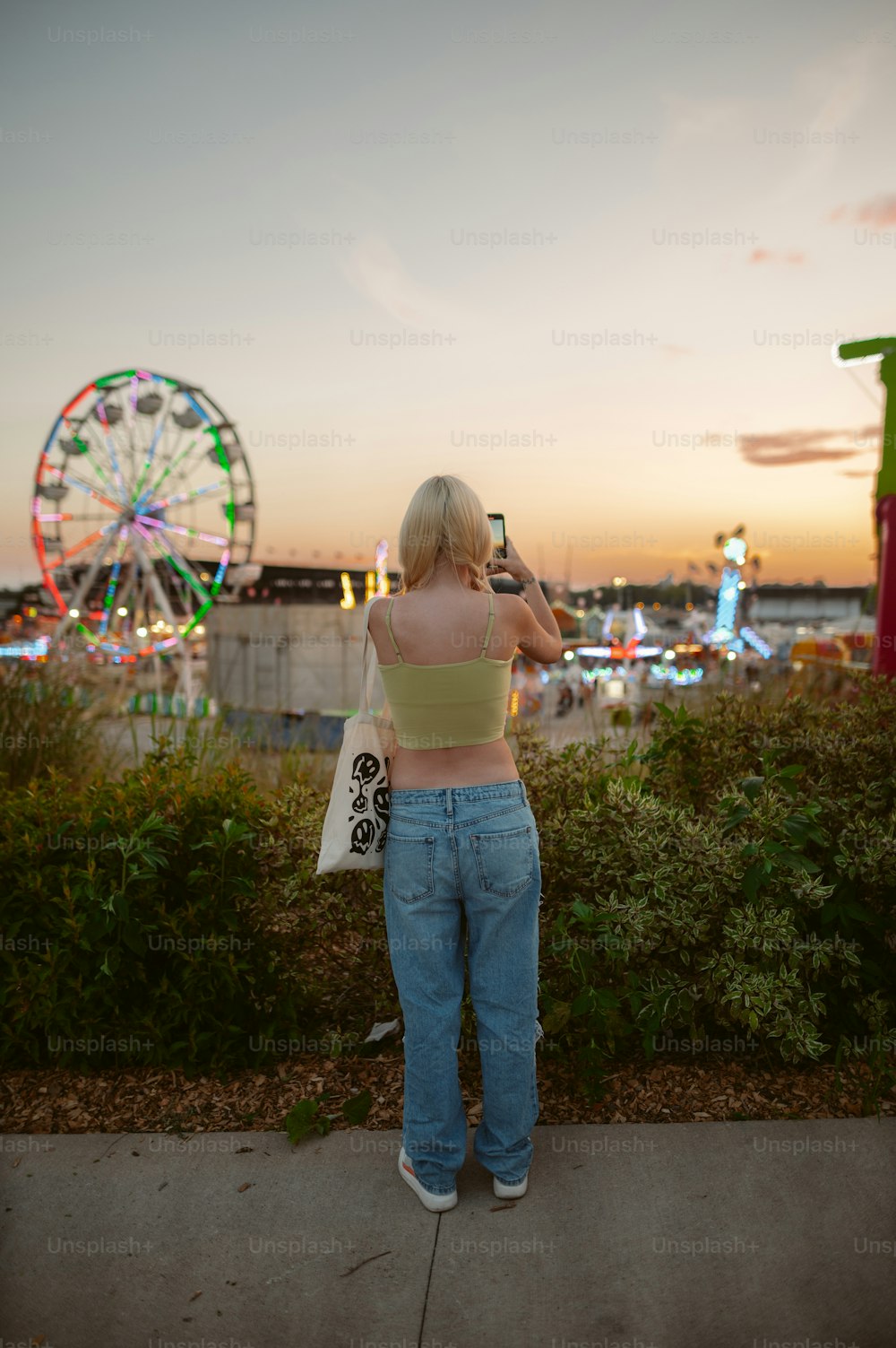 a woman taking a picture of a ferris wheel