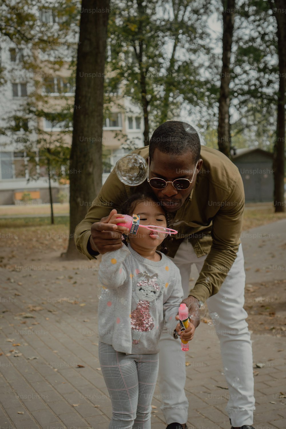 a man helps a little girl brush her teeth