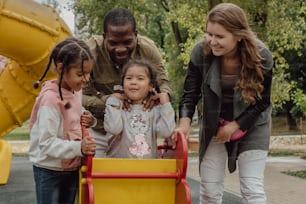 a group of people standing around a little girl in a yellow wagon