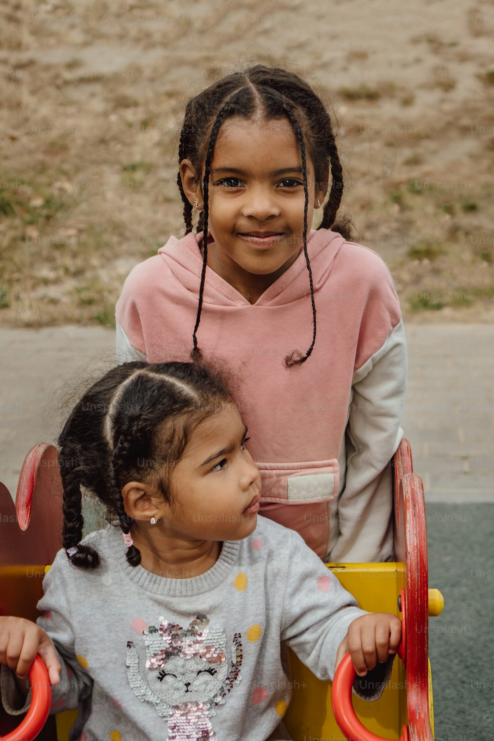 장난감 자동차에 앉아 있는 두 어린 소녀